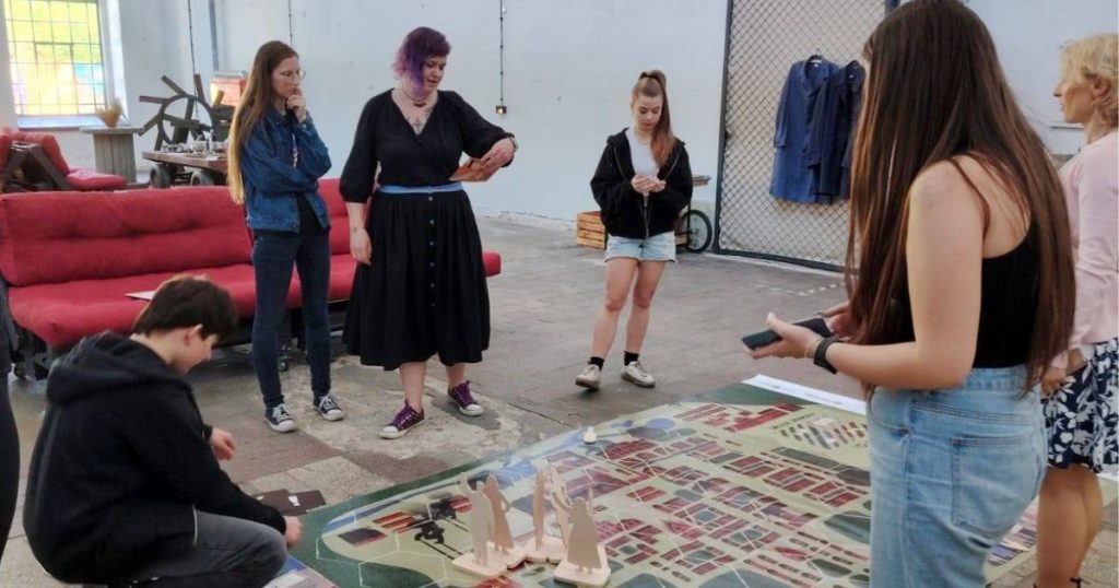 Grupa osób stoi wokół planzy go wielkoformatowej gry planszowej