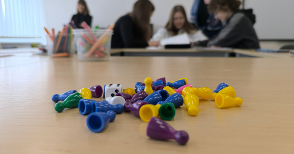 Pionki i kostki do gry. W tle uczestniczki warsztatów w Słupcy wraz z trenerką